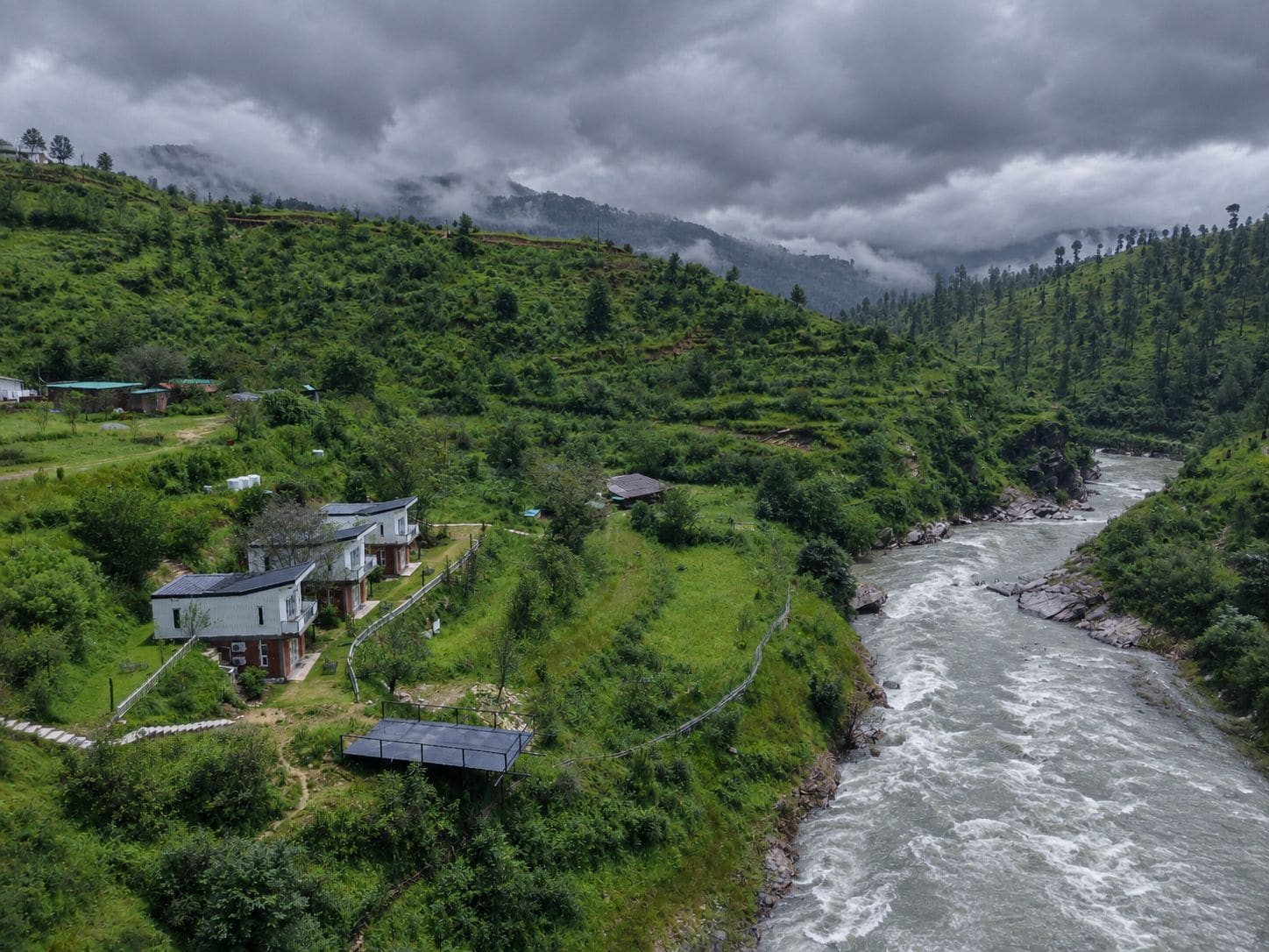 Un río serpentea por un valle verde y exuberante con casas a sus orillas.