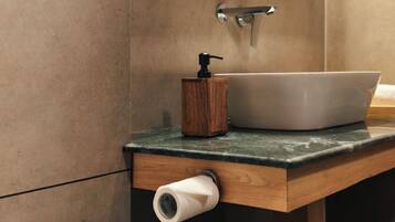 Un baño con tocador de madera, un lavamanos blanco, un espejo y un dispensador de papel higiénico.
