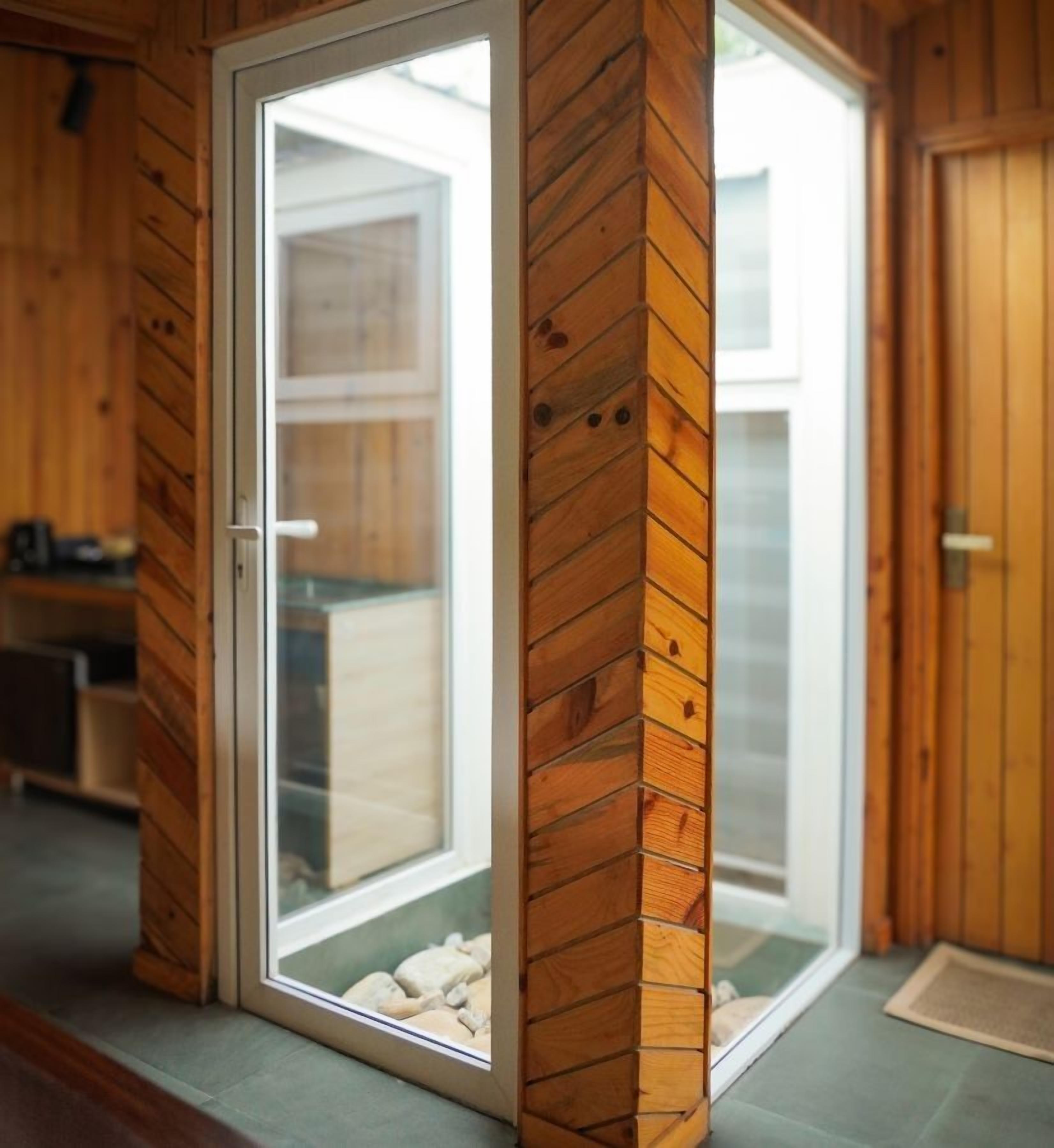 Une porte-fenêtre coulissante à cadre en bois donnant sur un espace extérieur agrémenté d’un chemin en pierre.