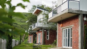 Ein modernes, zweistöckiges Gebäude mit Balkon, Ziegelaußenwand und einem Rasen mit Gartenmöbeln.