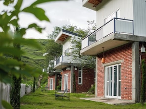 Un edificio moderno de dos plantas con balcón, fachada de ladrillo y jardín con muebles de exterior.