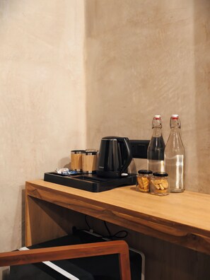 A kitchenette with a coffee maker, two glass bottles, and jars of food.