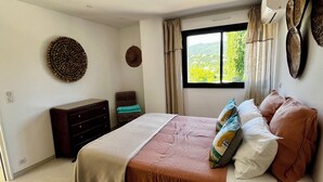 A bedroom with a bed, dresser, and a window with a view. - Villa Céleste, Apartment in villa, Swimming pool, garden, quiet, near the sea (Cavalaire-sur-Mer)