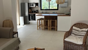 A modern living room with a sofa, a wicker chair, and a coffee table. - Villa Céleste, Apartment in villa, Swimming pool, garden, quiet, near the sea (Cavalaire-sur-Mer)