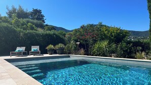 A swimming pool with two lounge chairs and potted plants. - Villa Céleste, Apartment in villa, Swimming pool, garden, quiet, near the sea (Cavalaire-sur-Mer)