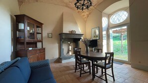 A cozy living room with a fireplace, a dining area with a table and chairs, and a large window offering a view of the outdoors. - Merula. Organic winery farm between Orvieto and Lake Bolsena (orvieto)