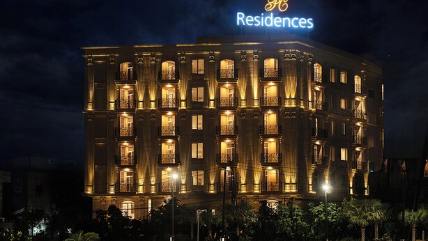 Ett hotell med flera våningar, upplysta balkonger och en tydlig skylt med texten ”Residences”.