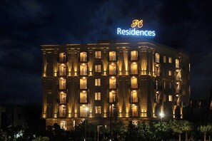 Ein mehrstöckiges Hotel mit beleuchteten Balkonen und einem gut sichtbaren Schild mit der Aufschrift 'Residences'.