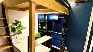 Una cocina moderna con refrigerador empotrado, estanterías de madera y una escalera que sube a un nivel superior.