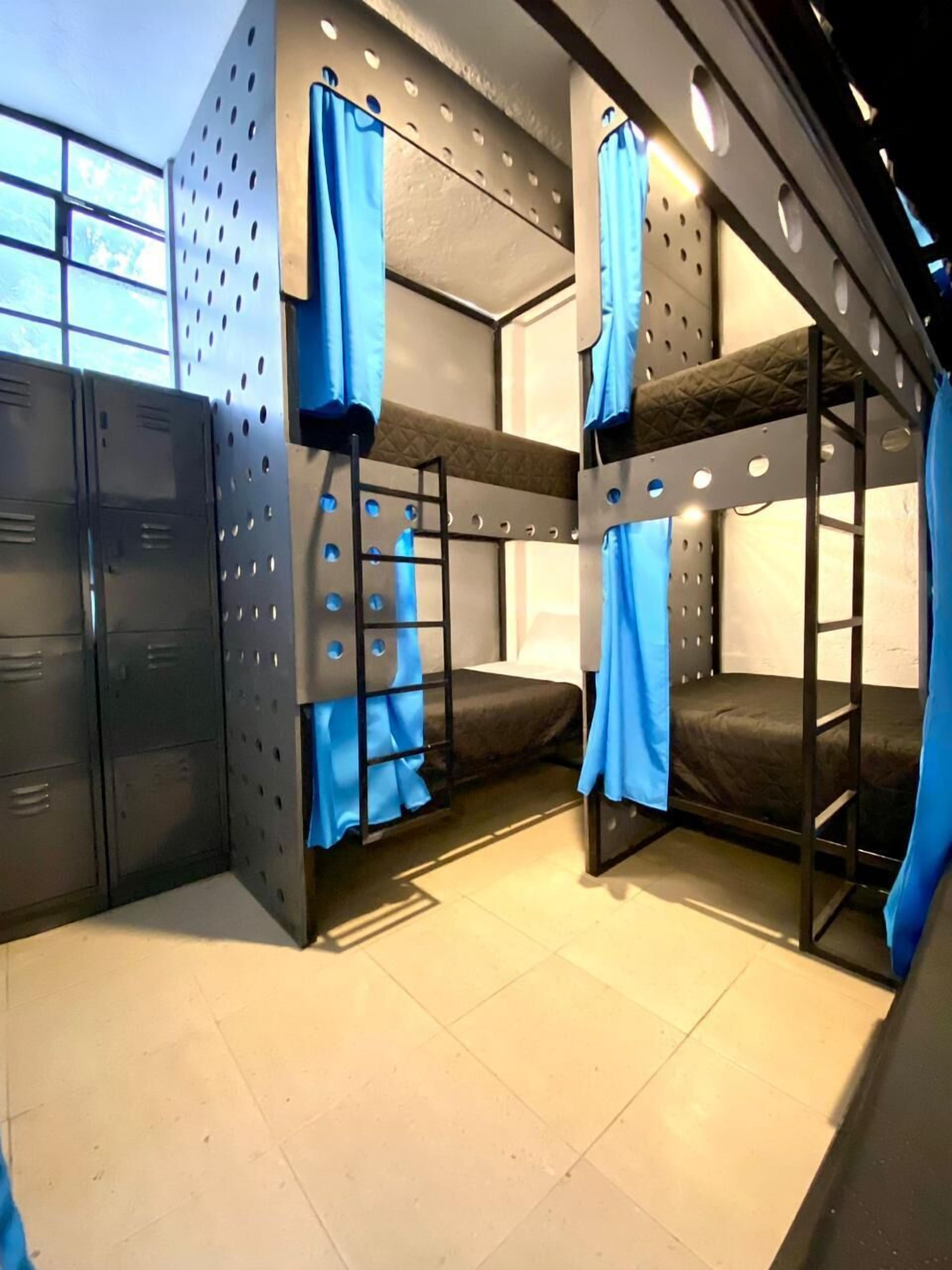 Habitación con literas, taquillas metálicas y una ventana.