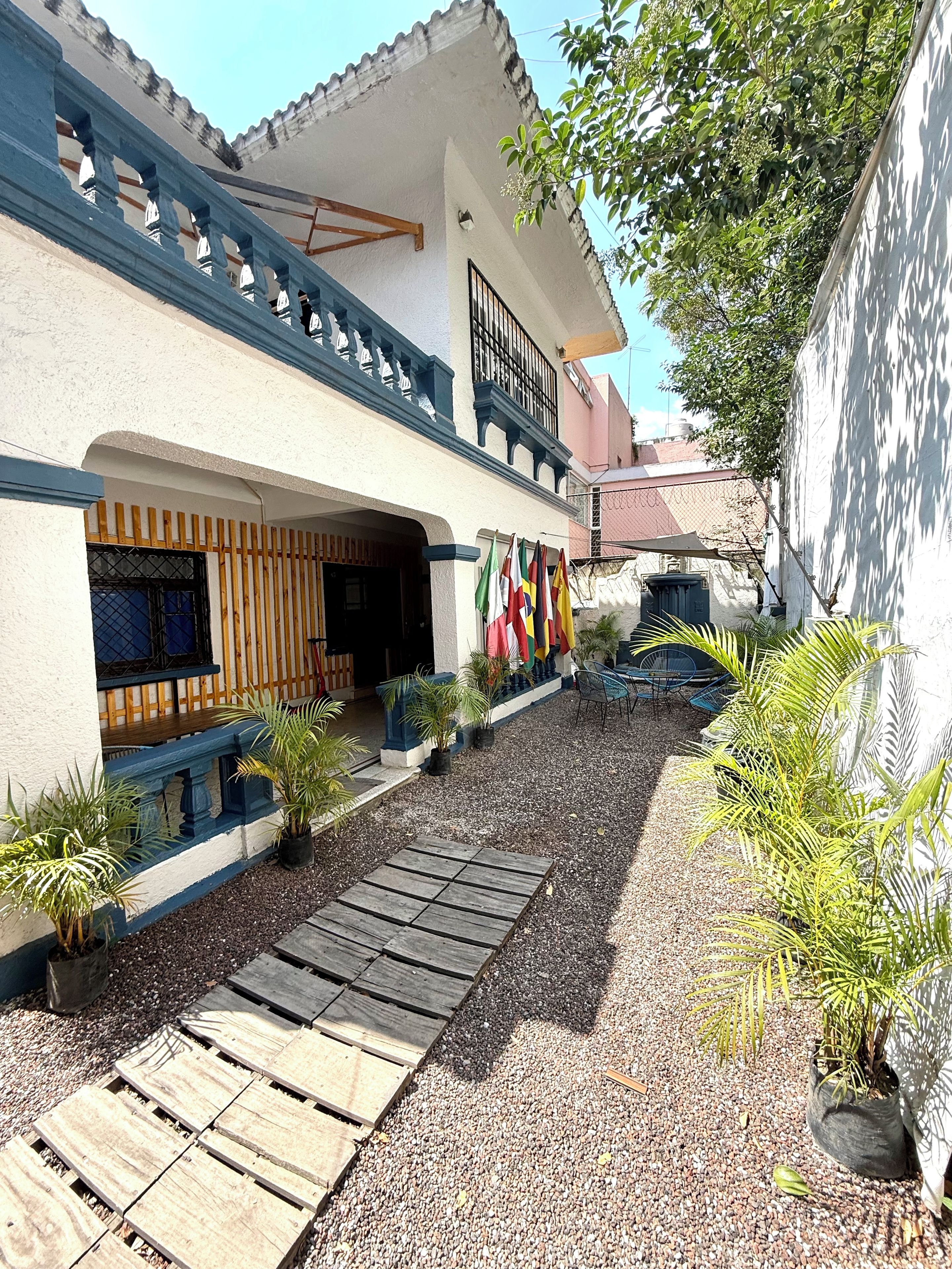 Un bâtiment doté d’un balcon, d’une entrée abritée et d’un chemin de gravier menant à l’entrée.