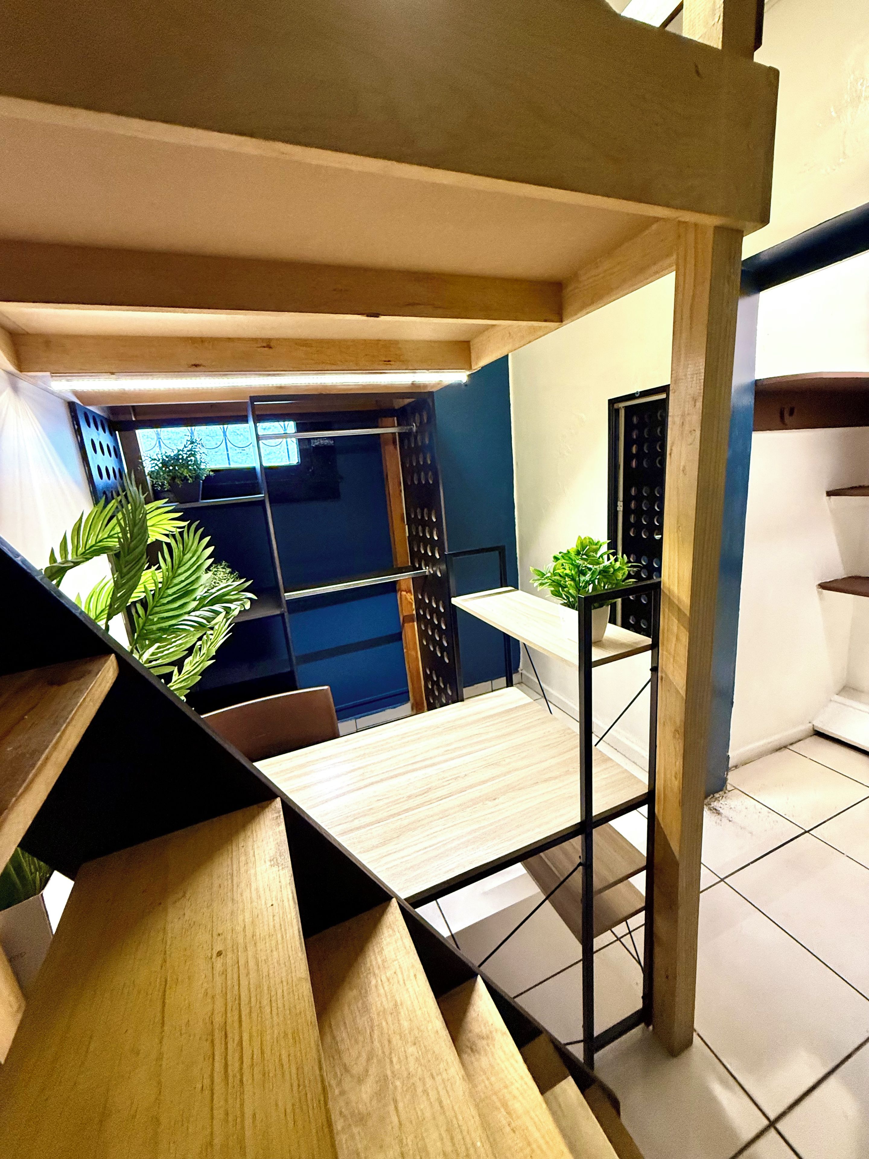 Un interior moderno con una escalera de madera, una pequeña mesa y una planta en maceta.