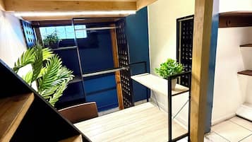 Un interior moderno con una escalera de madera, una pequeña mesa y una planta en maceta.