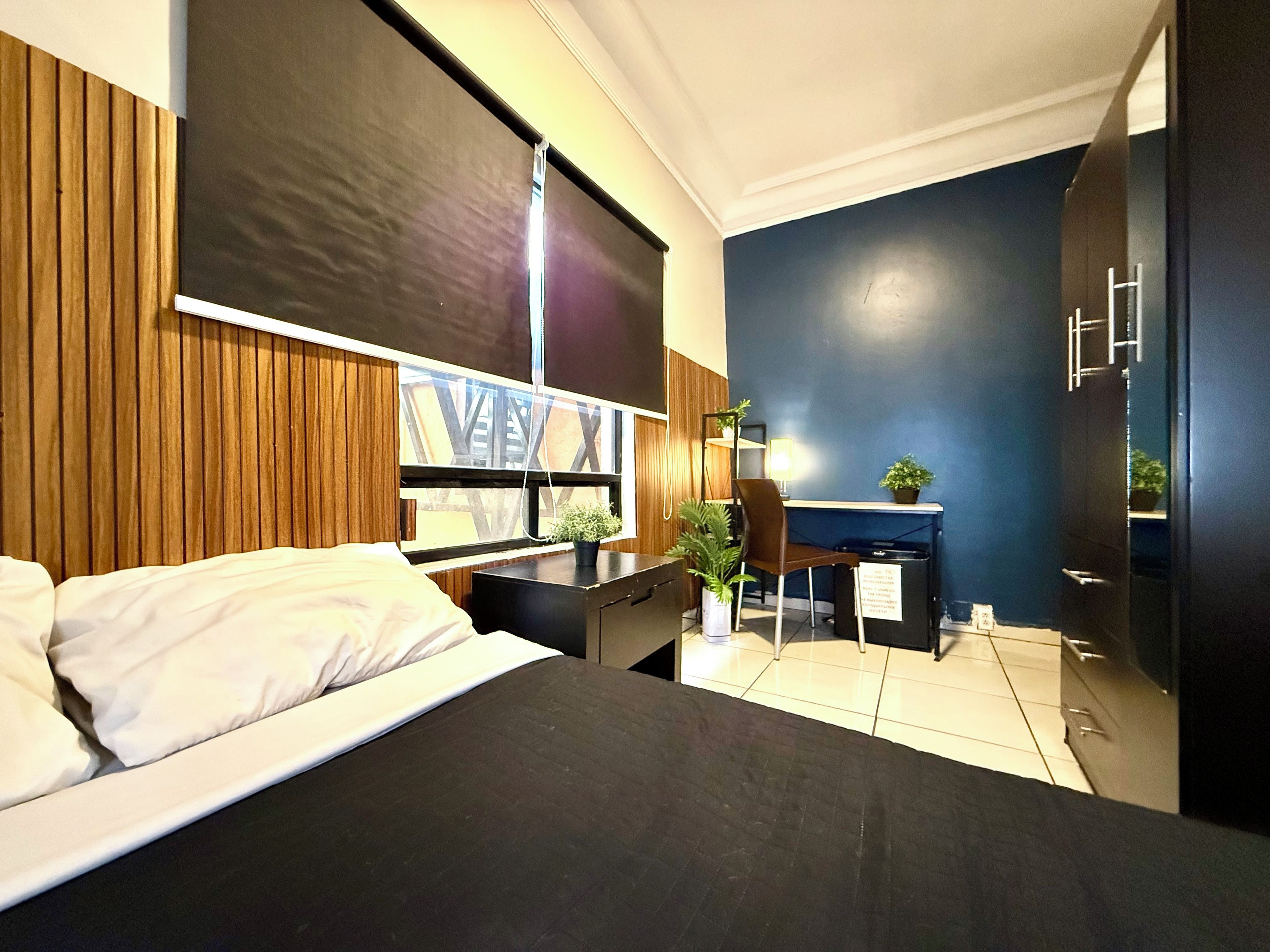 A modern hotel room with a bed, desk, chair, and a view of the outside.