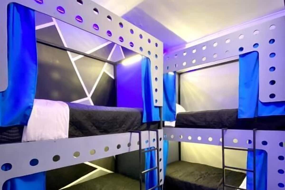 A bunk bed room with a geometric wall design and blue curtains.