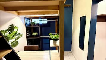 Una escalera conduce a un comedor con una mesa y sillas, rodeado de plantas en macetas y una pared azul.