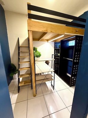 A room with a wooden ladder, a table, and a shelving unit with circular cutouts.