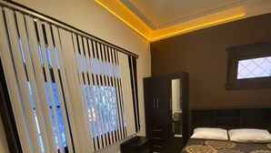 A bedroom with a bed, desk, chair, wardrobe, and a window with blinds. - RMS Hostal - Roma (Mexico City)