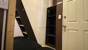 A narrow stairway leading to a lower level, a white door, and a black shelving unit against the wall. - RMS Hostal - Roma (Mexico City)