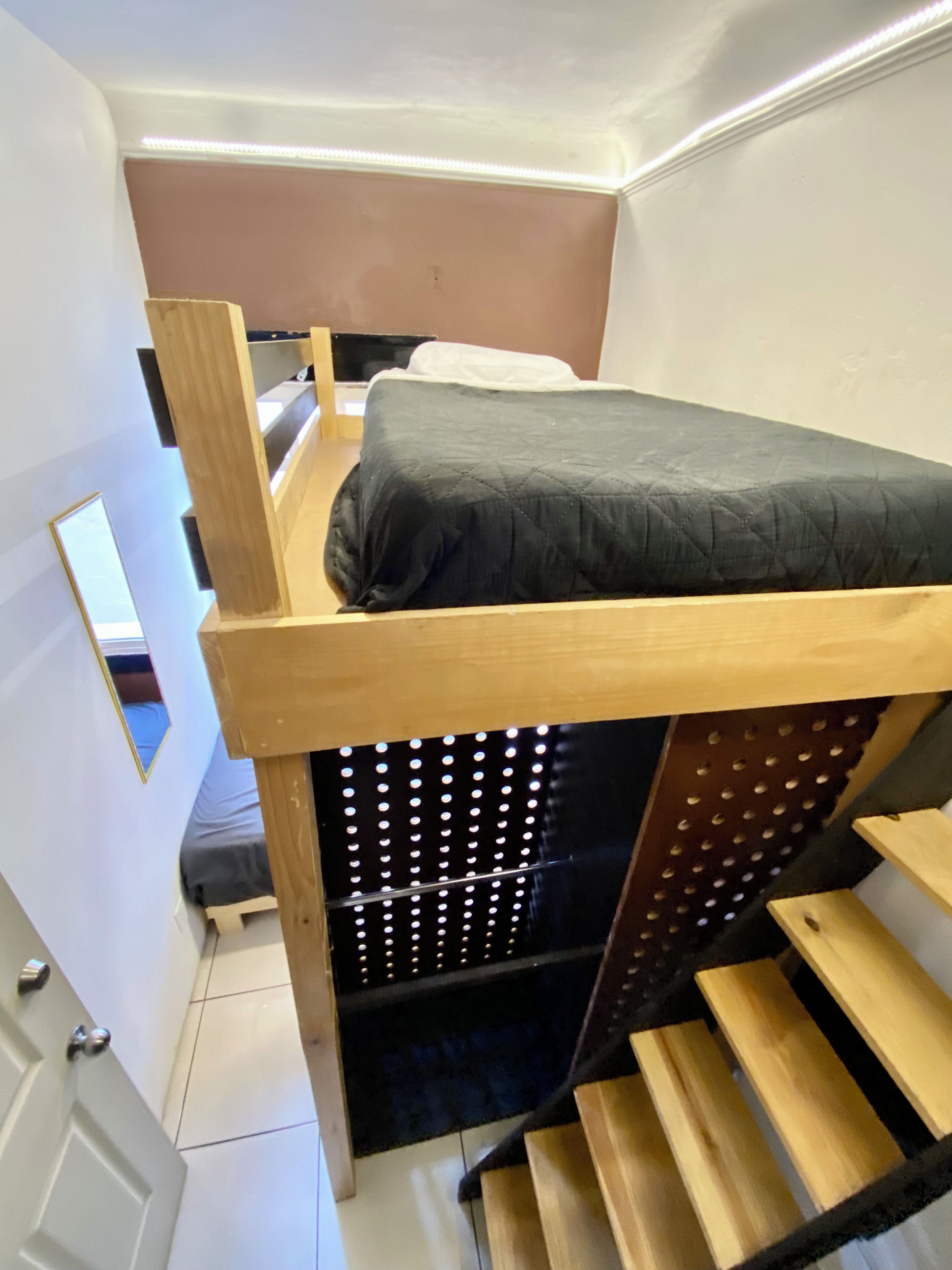 A bunk bed with a wooden frame, a mattress, and a black headboard.