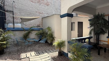 Un patio con terraza de madera, mobiliario exterior y plantas en macetas.