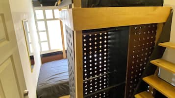 Una habitación pequeña con literas, un escritorio y una ventana.