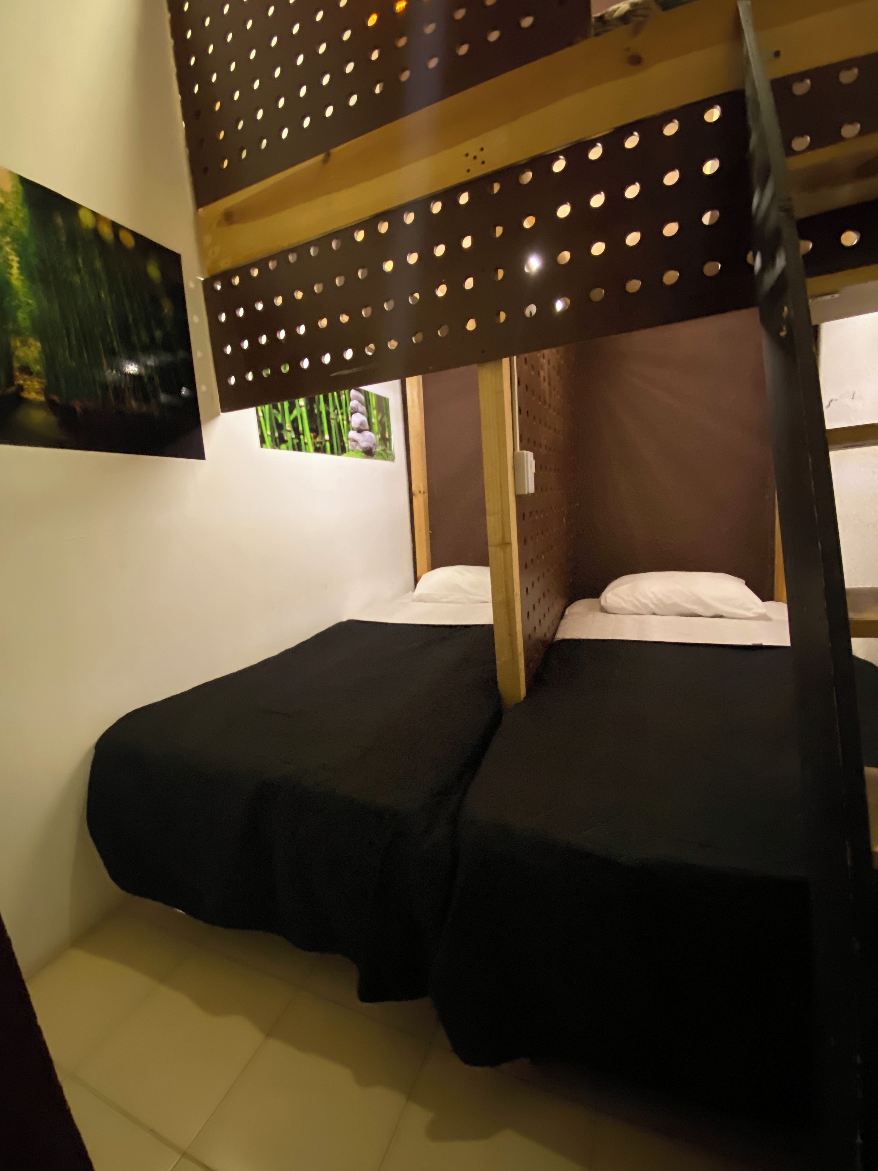 A bunk bed room with a wooden slat ceiling and a small window with a view of greenery.