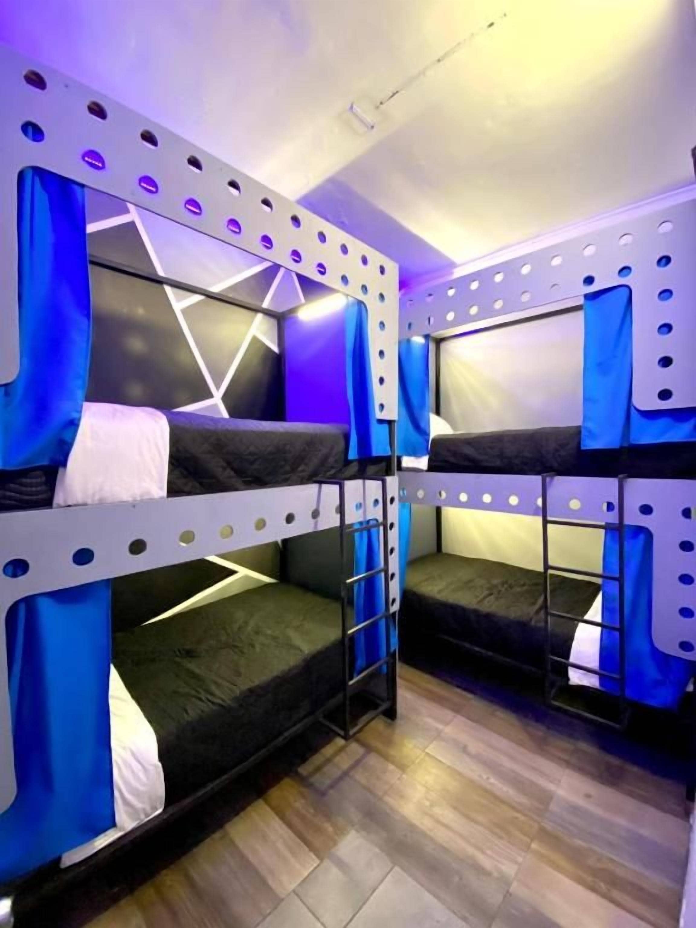 Habitación con literas y un diseño geométrico en la pared, con cortinas azules.