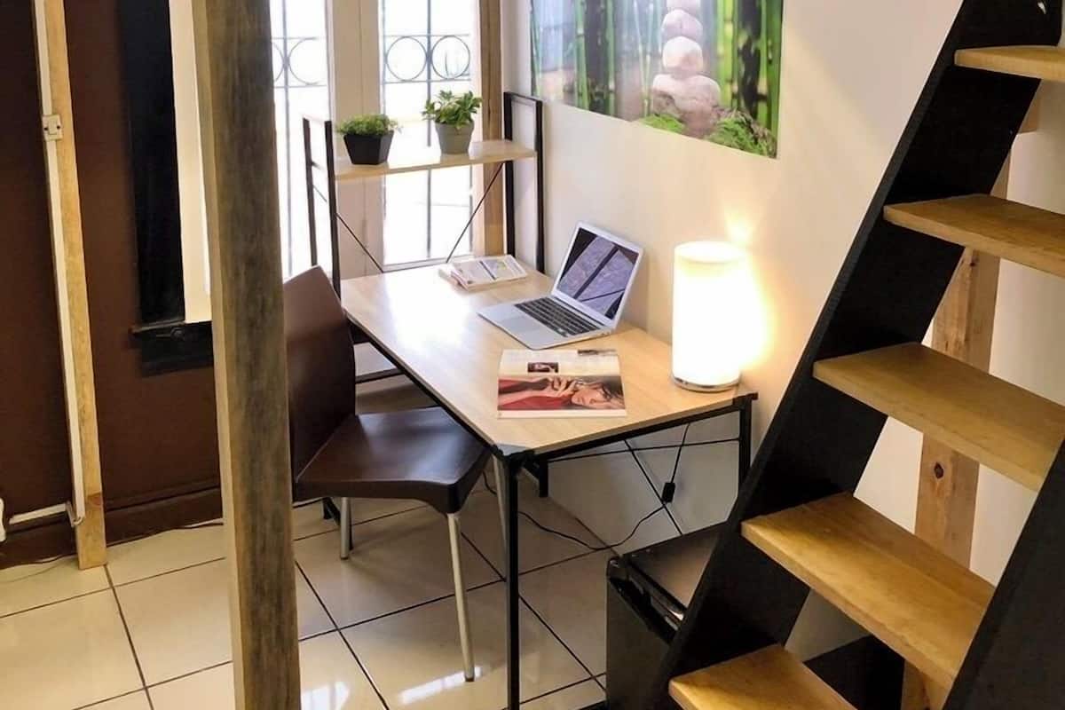 A bunk bed with a desk underneath, a laptop, a lamp, and a framed picture on the wall.