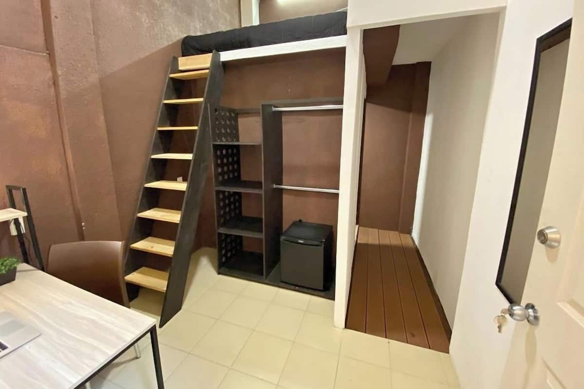 A compact room with a bunk bed, a desk, and a small storage area.