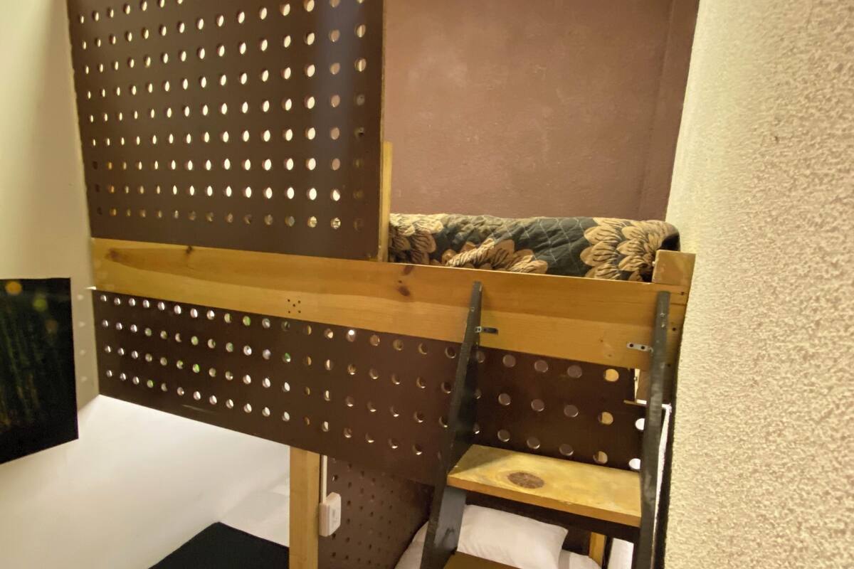 A bunk bed with a wooden ladder and a perforated headboard.
