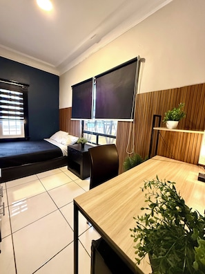 Una camera moderna con un letto, una scrivania, una sedia, una TV e una finestra con tende.