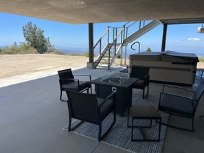 Patio esterno con set da pranzo, barbecue e una scala che conduce a un piano superiore.