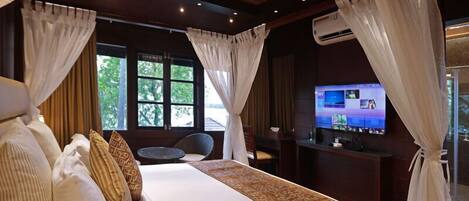A hotel room with a large bed, a TV, and a window with curtains.