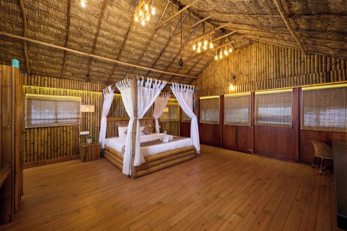 Une pièce dotée d’un plancher en bois, d’un lit à baldaquin et d’un plafond recouvert de chaume.