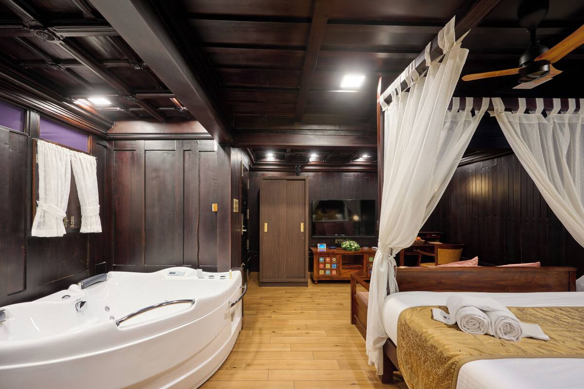 Une chambre d’hôtel avec une grande baignoire, un lit à baldaquin et un téléviseur dans un coin.