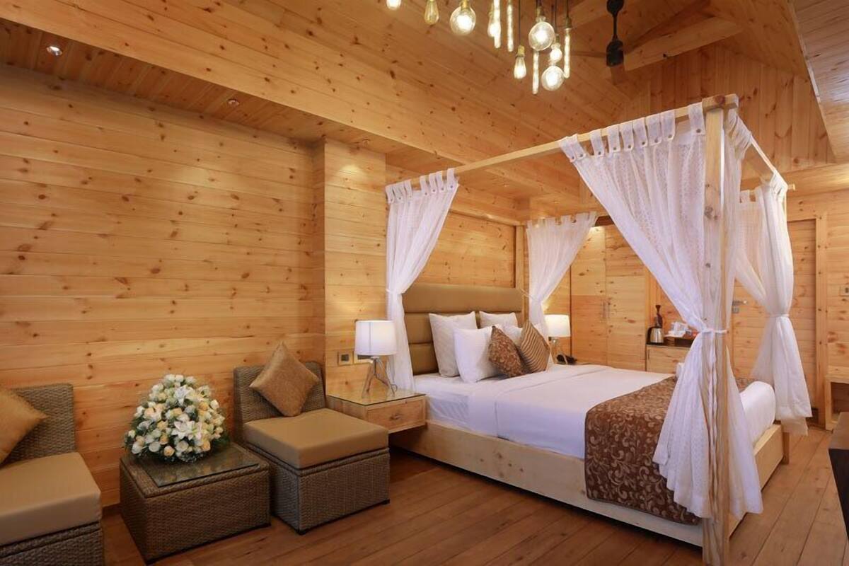 Une chambre à coucher de style cabane en bois, avec un lit à baldaquin, des meubles en osier et une table de chevet avec une lampe.