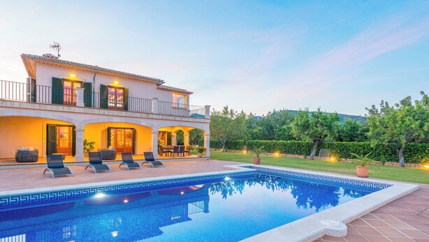 A two-story villa with a swimming pool, outdoor seating, and a well-maintained garden.