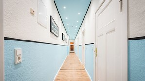 Un passadís amb parets de blau clar, fusta al terra i portes blanques.