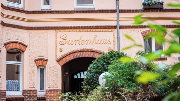Un edifici amb un rètol que diu "Gartenhaus" i un arc de maó.