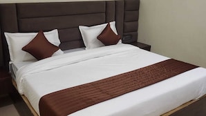Ein Bett mit dunkelbrauner Kopfteil, weißer Bettwäsche und braunen Kissen.