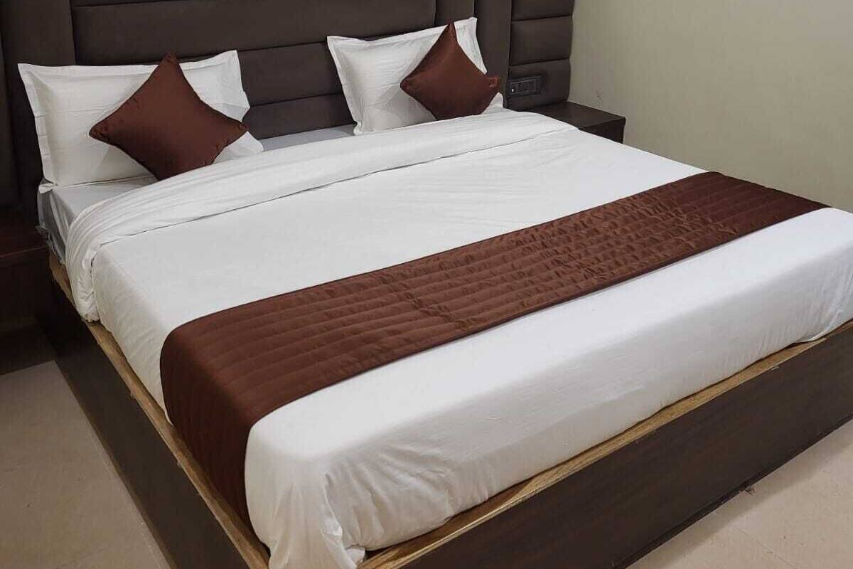 Un letto con una testiera scura, biancheria da letto bianca e cuscini marroni.