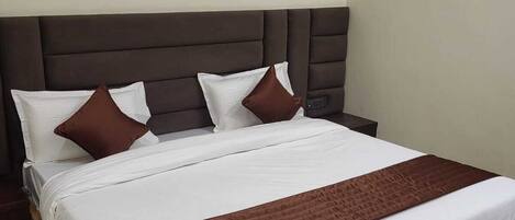 A bed with a dark headboard, white bedding, and brown pillows.