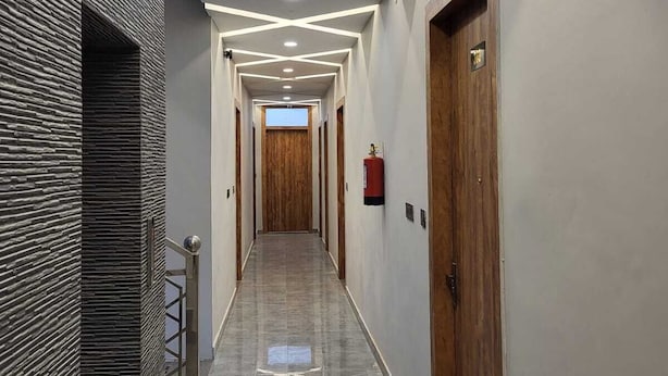 Ein modern gestalteter Flur mit spiegelndem Boden, einer Holztür rechts und einer strukturierten Wand links.