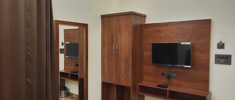 A bathroom with a wooden vanity, a mirror, a television mounted on the wall, and a shower curtain.