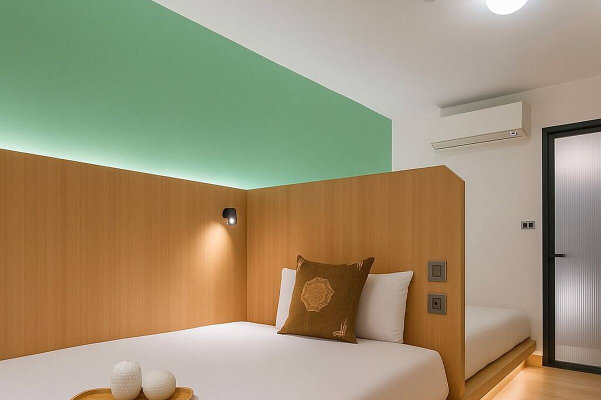 Een moderne hotelkamer met een groot bed, een houten hoofdeinde en een groene accentmuur.