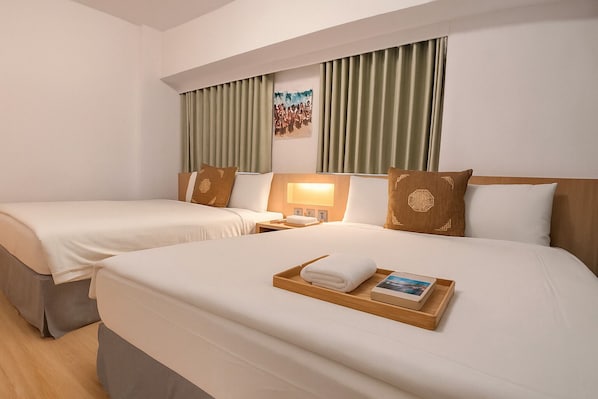 A hotel room with two beds, a wooden headboard, a bedside table with a lamp, and a tray with a towel and a book. - Moonsset INN Taitung (Taitung)