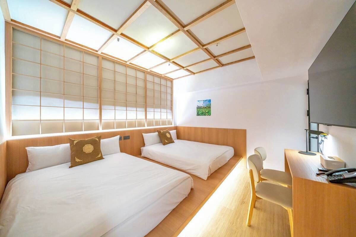 Een hotelkamer met twee bedden, een bureau en een stoel.