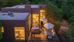 A modern house with a deck, a hot tub, and a dining area with outdoor furniture. - Enchanted Waters Retreat (Sedona)