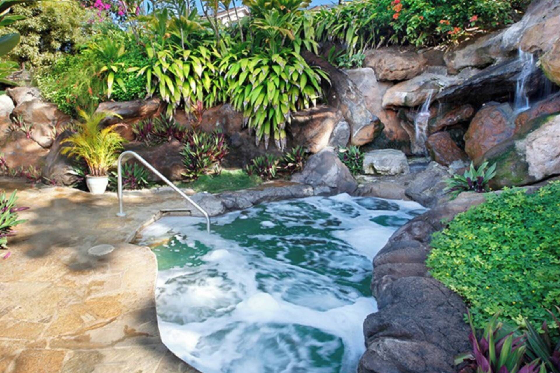 A hot spring surrounded by rocks and lush greenery.